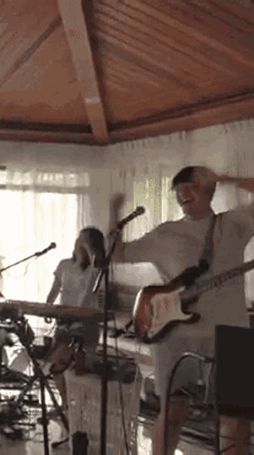 a man is playing a guitar and a woman is playing a keyboard in a living room .