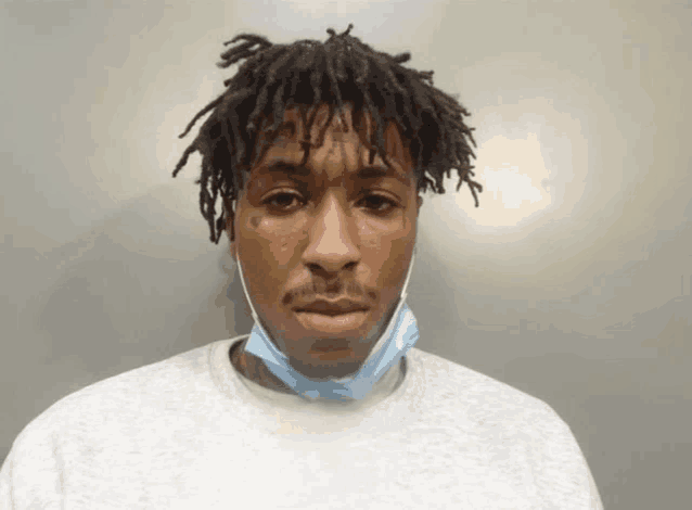 a man with dreadlocks and a tattoo on his face wears a mask