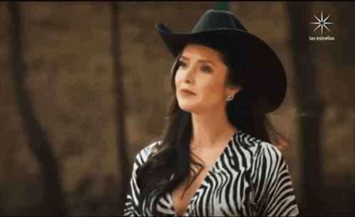a woman wearing a zebra print shirt and a cowboy hat with las estrellas written in the corner