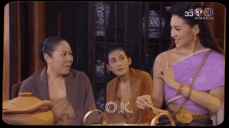 three women are sitting at a table and talking to each other .