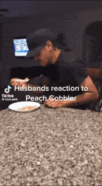 a man is sitting at a counter with a plate of food and a tiktok video titled husbands reaction to peach cobbler
