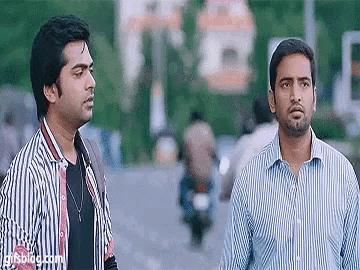 two men are standing next to each other on a street with a gifsblog.com logo on the bottom right