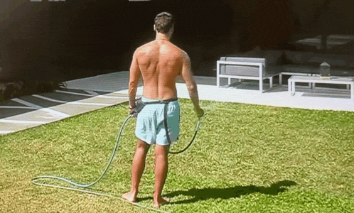 a shirtless man in blue shorts is holding a hose in his hand