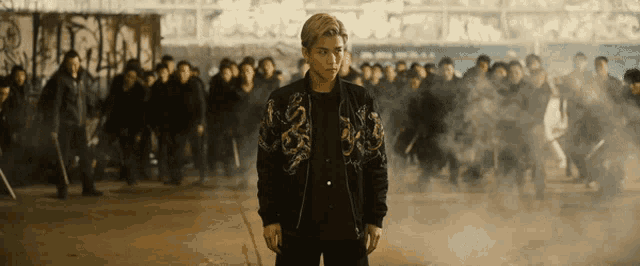 a man in a black jacket is standing in front of a crowd