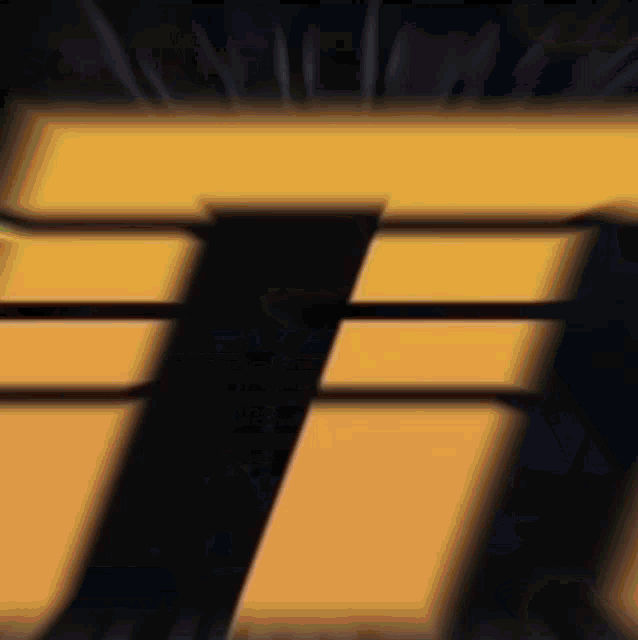 a close up of a yellow and black letter t on a black background