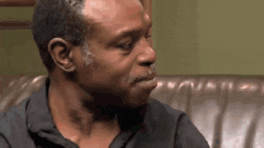 a man is sitting on a couch with his eyes closed and making a funny face .