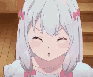 a girl with gray hair and pink bows on her hair is making a funny face .