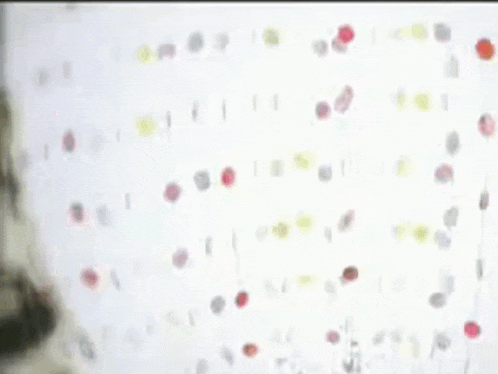 a woman in a white dress is standing in front of a wall with dots on it