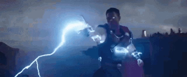 a man is holding a lightning bolt in his hand while standing in the dark .