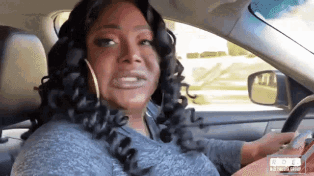 a woman is driving a car and making a face .