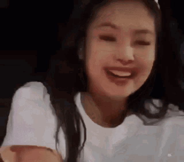 a close up of a woman wearing a white t-shirt and making a funny face .