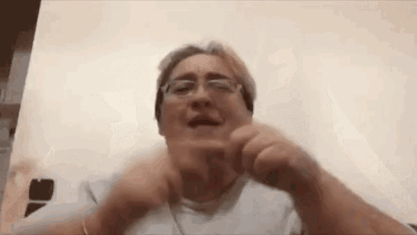 a woman wearing glasses is making a funny face and making a funny face with her hands .