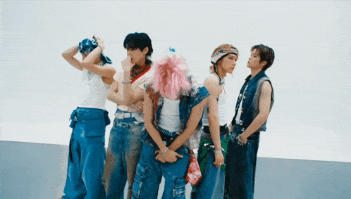a group of young men standing next to each other with one wearing a pink wig
