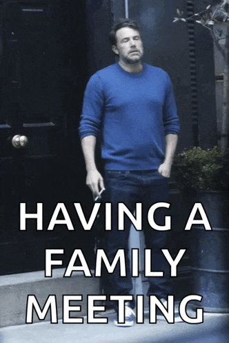 a man in a blue sweater is smoking a cigarette with the caption having a family meeting
