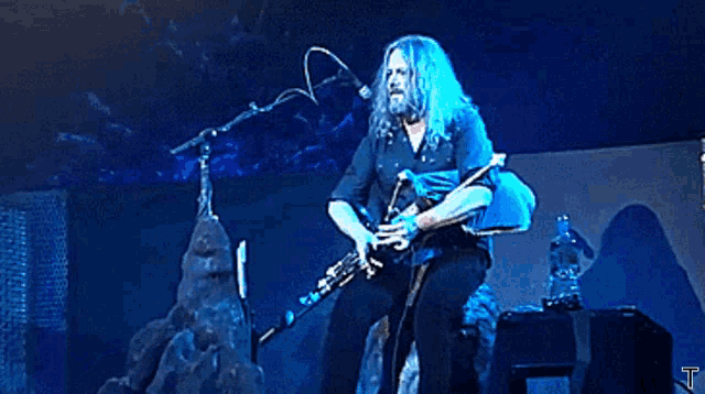a man with long hair playing a bagpipe on stage