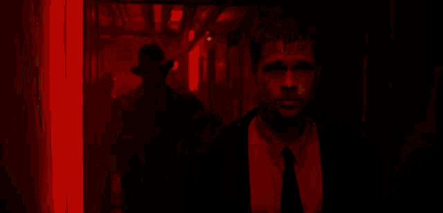 a man in a suit and tie is standing in a red room .