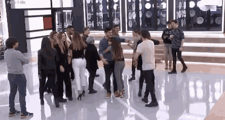 a group of people are standing in a room with a woman hugging a man .