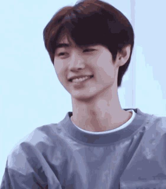 a close up of a young man wearing a blue sweater and smiling .