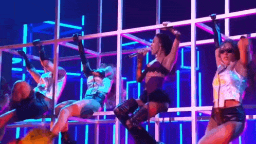 a group of women are dancing on a stage in front of a microphone .