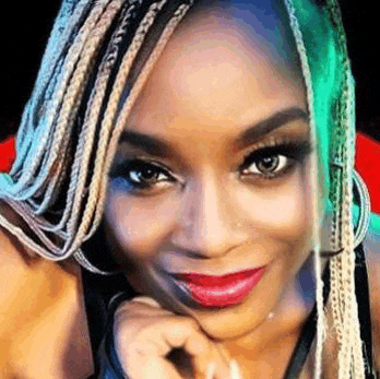 a close up of a woman with braids and red lipstick .