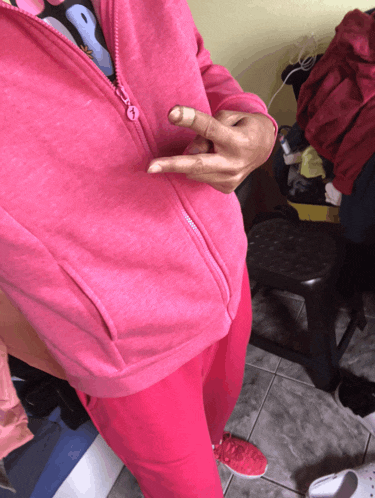 a person wearing a pink hoodie and pink sweatpants giving the middle finger