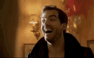 a man is smiling with his mouth open in a room with balloons .