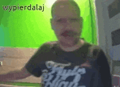 a man with a mustache is standing in front of a green background .