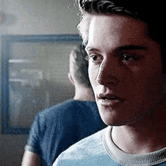a young man in a blue shirt is looking at something