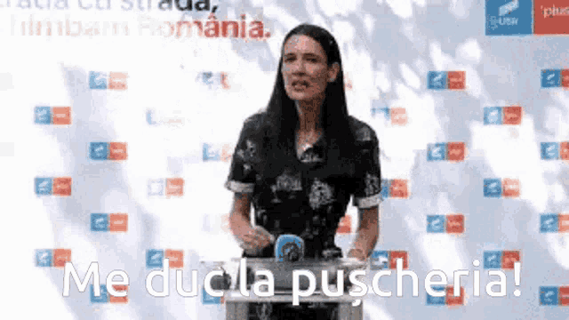 a woman is standing in front of a sign that says me duc la puscheria