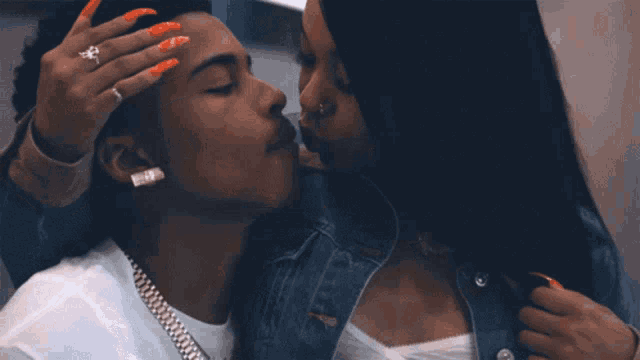a woman kisses a man on the forehead while he holds her hand