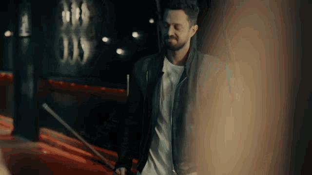 a man with a beard wearing a black leather jacket and white shirt