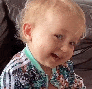 a baby is sitting on a couch wearing a zebra print jacket and smiling .