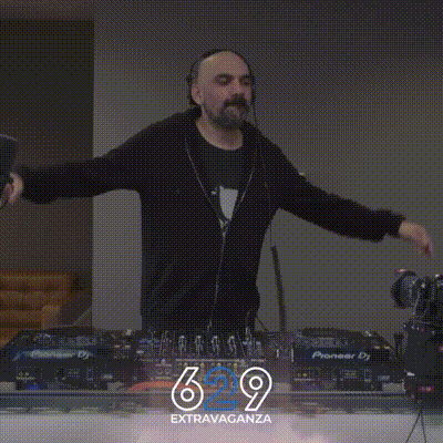 a man wearing headphones stands in front of a pioneer dj machine