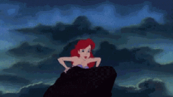 ariel is sitting on a rock in the ocean .