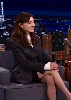 a woman in a suit is sitting in a chair with her legs crossed .