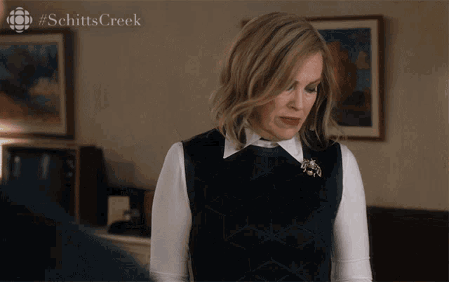 a woman with a #schittscreek logo on the bottom right