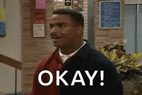 a man is standing in a room with a sign that says `` okay ! ''