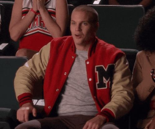 a man wearing a varsity jacket with the letter m on it