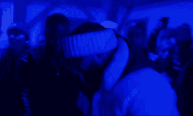 a blurry picture of a person in a dark room with a blue light behind them