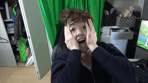 a person sitting in front of a green screen covering their face