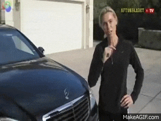 a woman is standing in front of a black mercedes and smoking a cigarette .