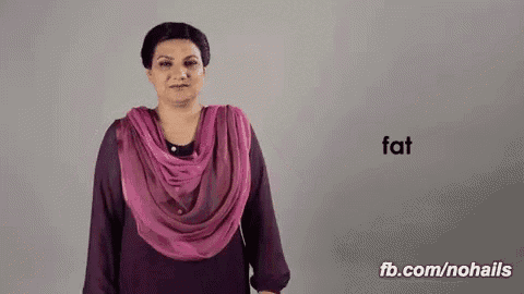a woman wearing a purple scarf is making a sign that says fat