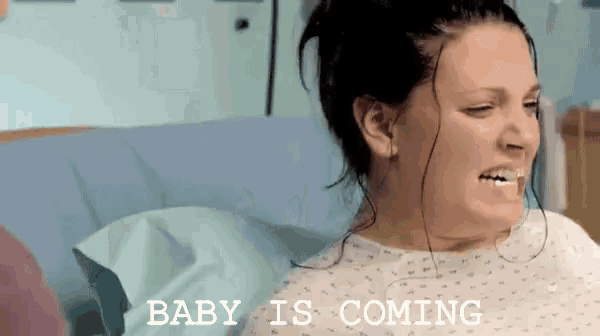 a woman in a hospital bed with the words baby is coming