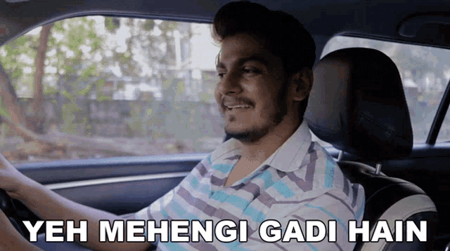 a man driving a car with the words yeh mehangi gandi hain written on the bottom