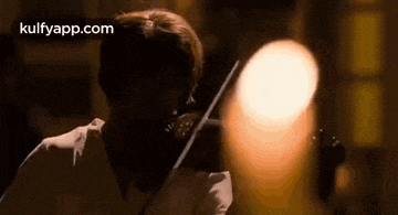 a woman is playing a violin in a dark room with a blurry background .