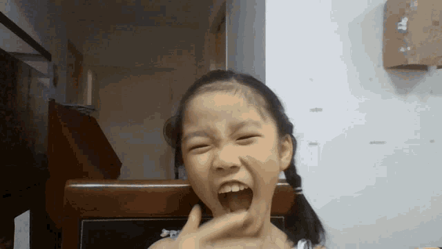a little girl is making a face with her mouth open