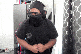 a man wearing a mask and headphones is standing in front of curtains
