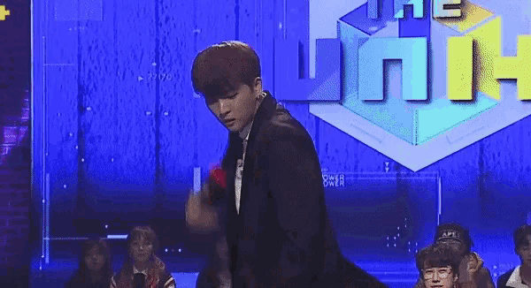 a young man in a suit and tie is dancing on a stage in front of a crowd .