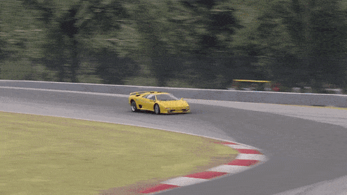 a yellow sports car is going around a curve on a race track