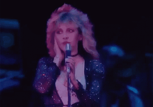 a woman is singing into a microphone in a dark room .